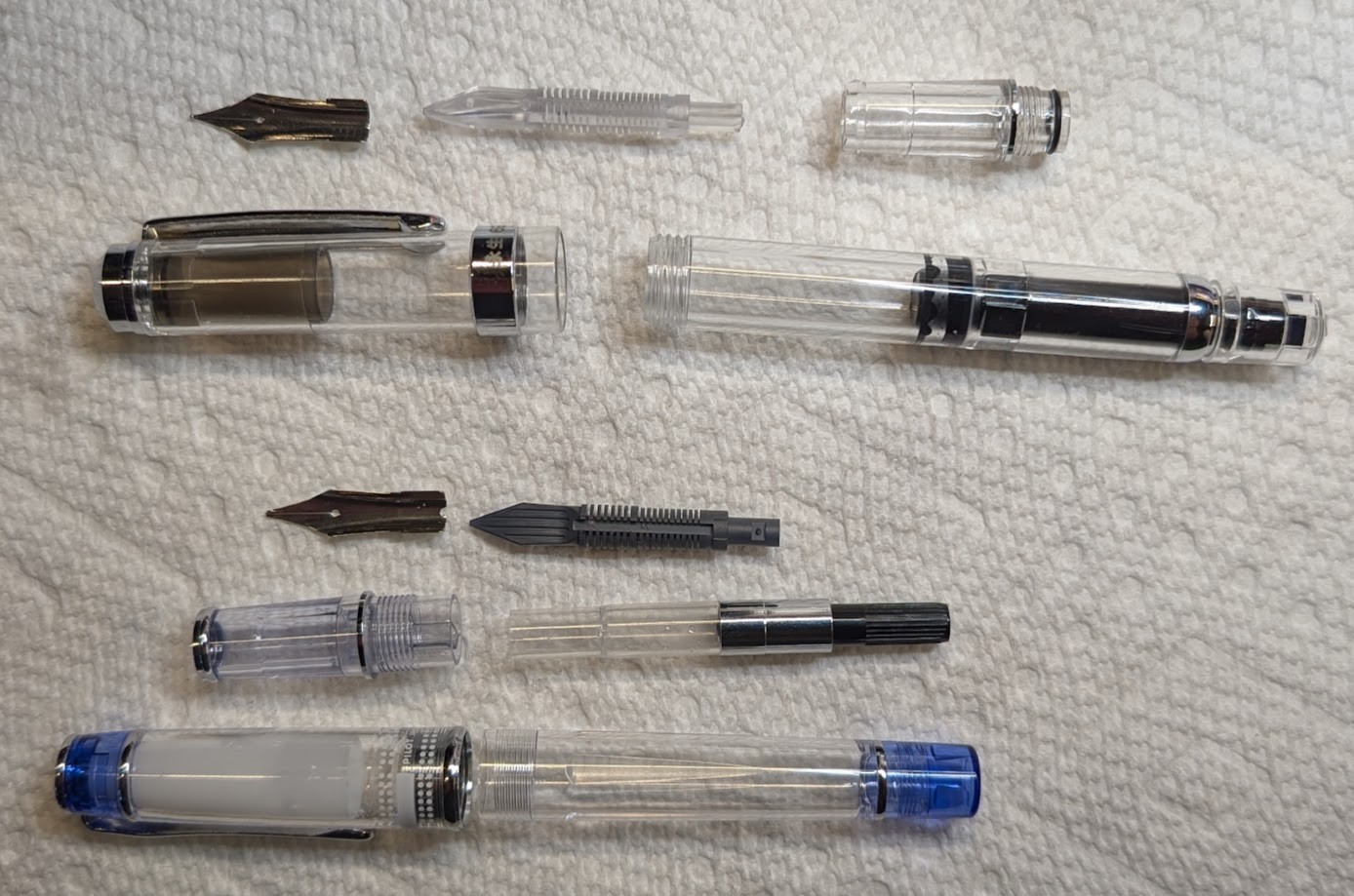 Photo of two disassembled fountain pens: A Wing Sung 698 and a Pilot Prera.