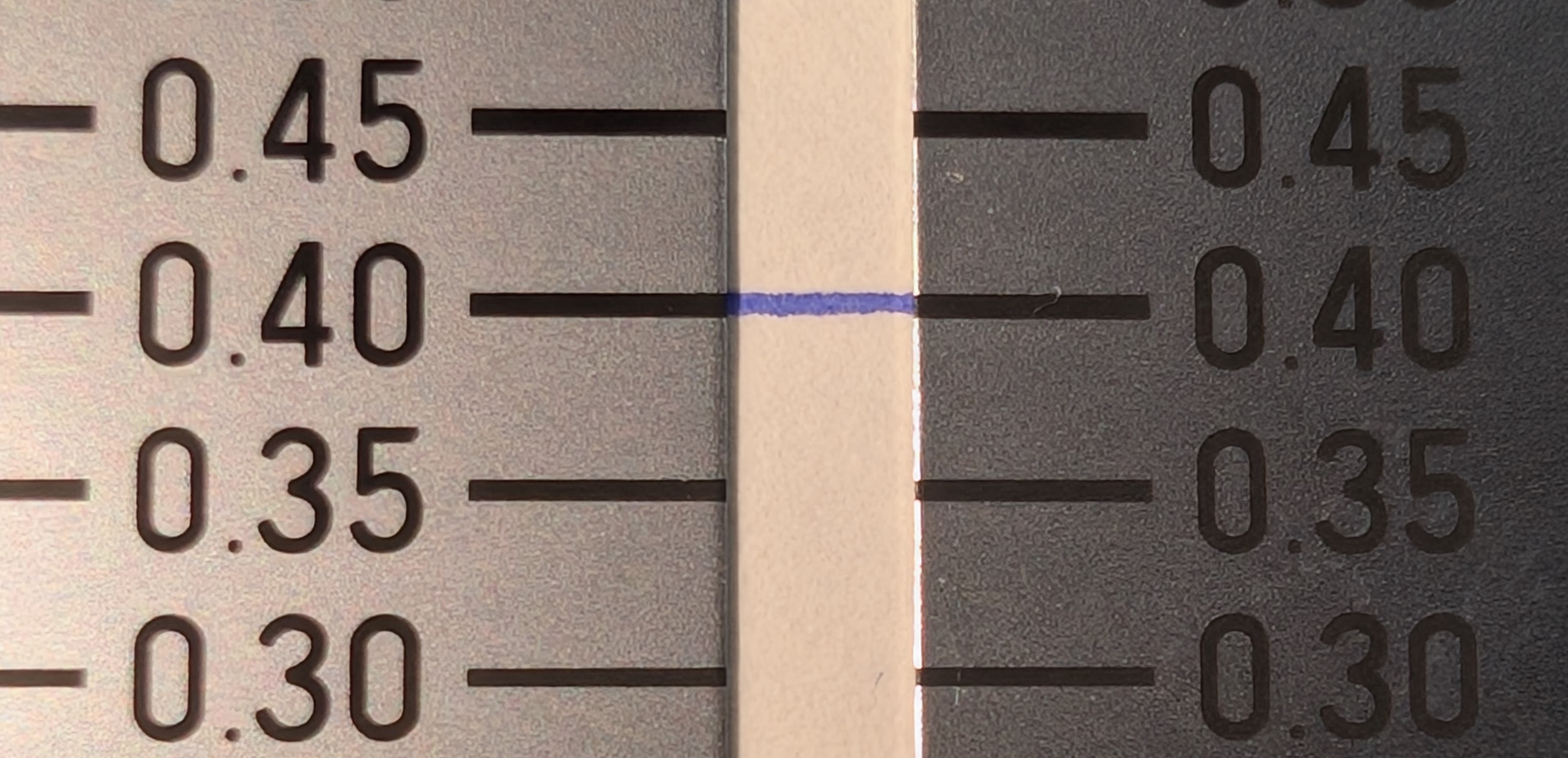 Photo of a crack gauge with line thicknesses measurements in fractions of a millimeter. There is a line of blue ink across the 0.40mm gauge lines and it appears to match the thickness.