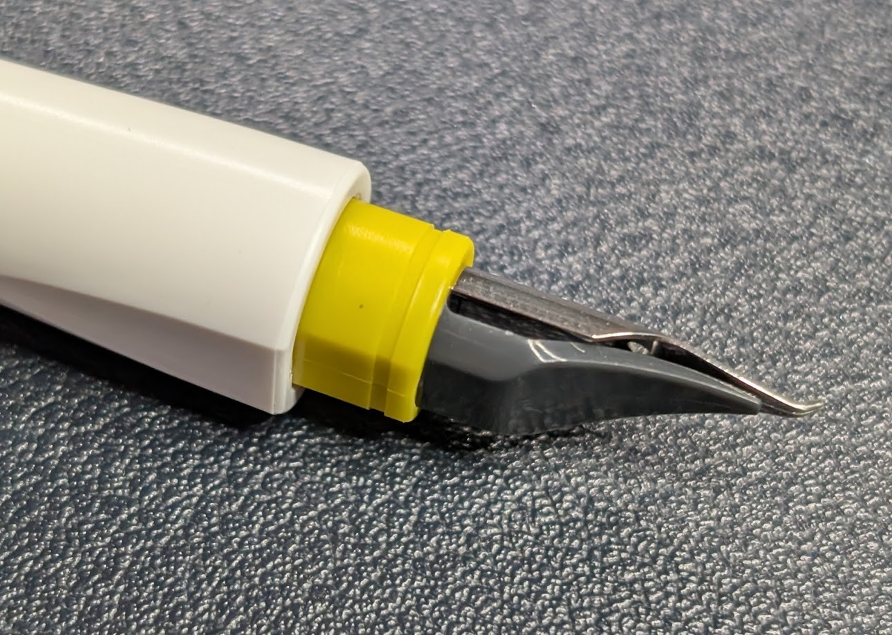 Close-up side view of the Fude nib with its upward bet tip nib. Under the nib is a dark gray plastic ink reservoir.