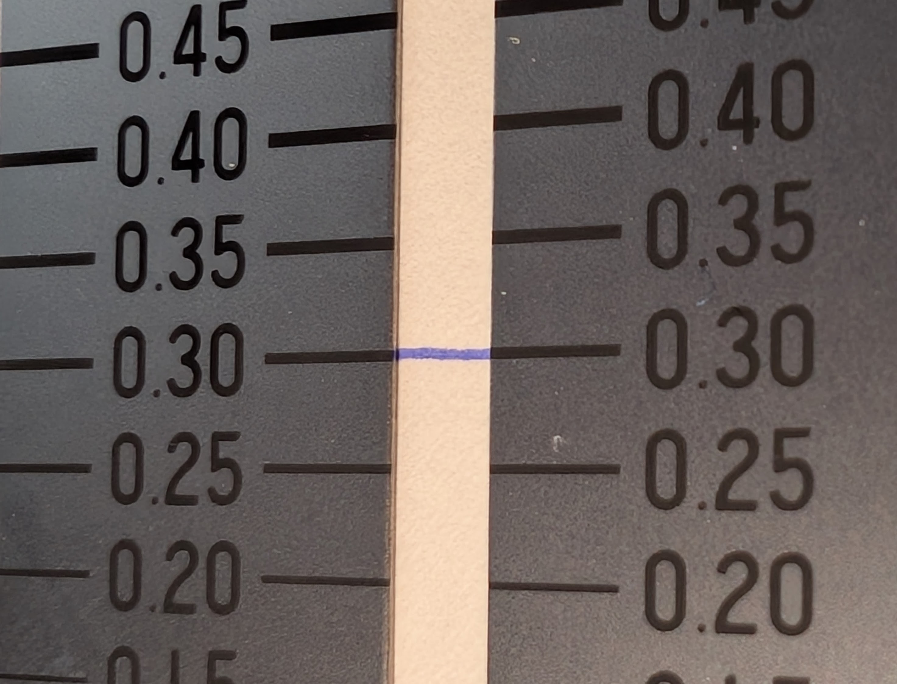Photo of a crack gauge with line thicknesses measurements in fractions of a millimeter. There is a line of blue ink across the 0.30mm gauge lines and it appears to match the thickness.