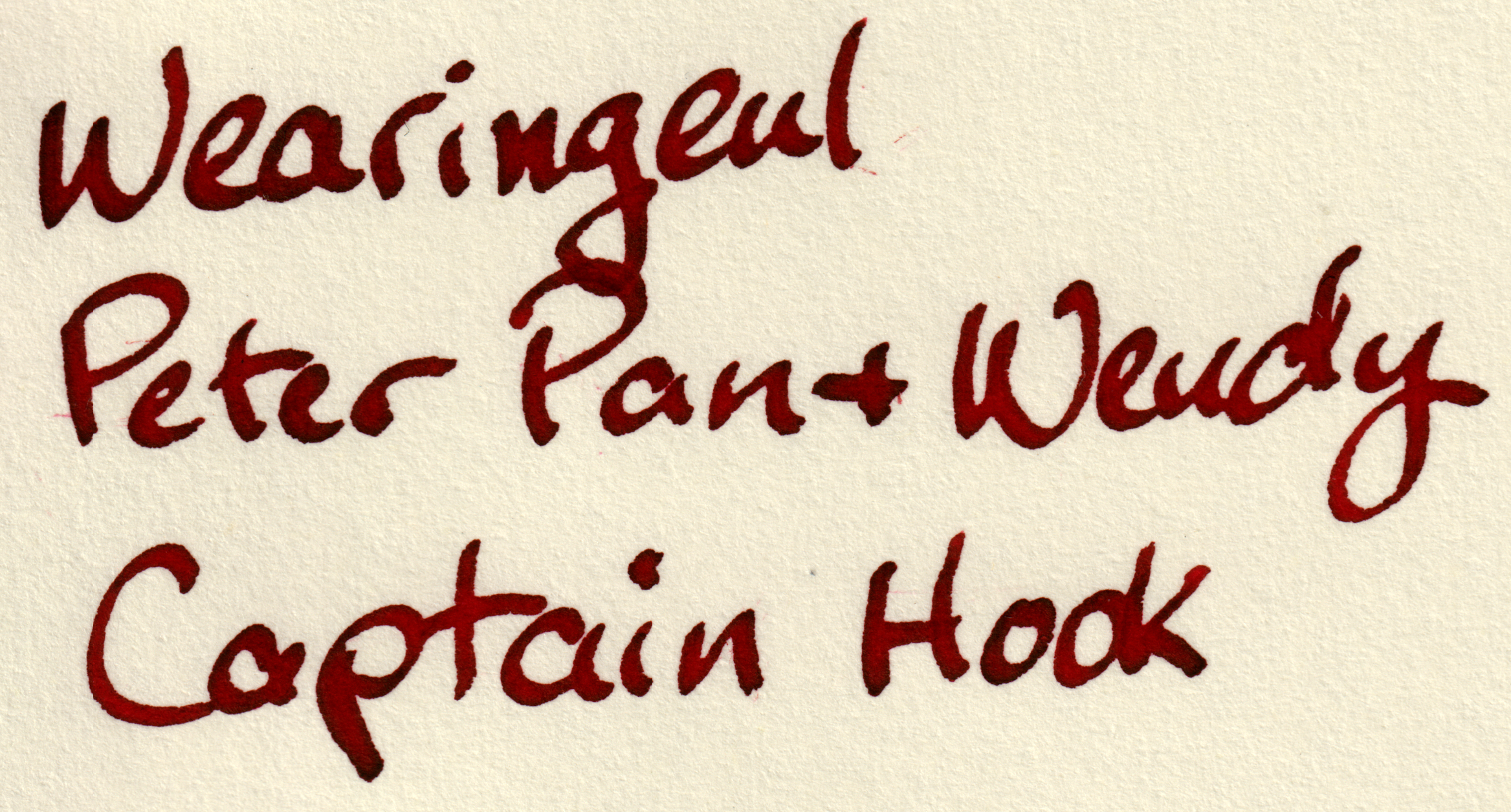 Scan of a writing sample on paper reading "Wearingeul / Peter Pan + Wendy / Captain Hook" in dark red ink with even darker red shading.