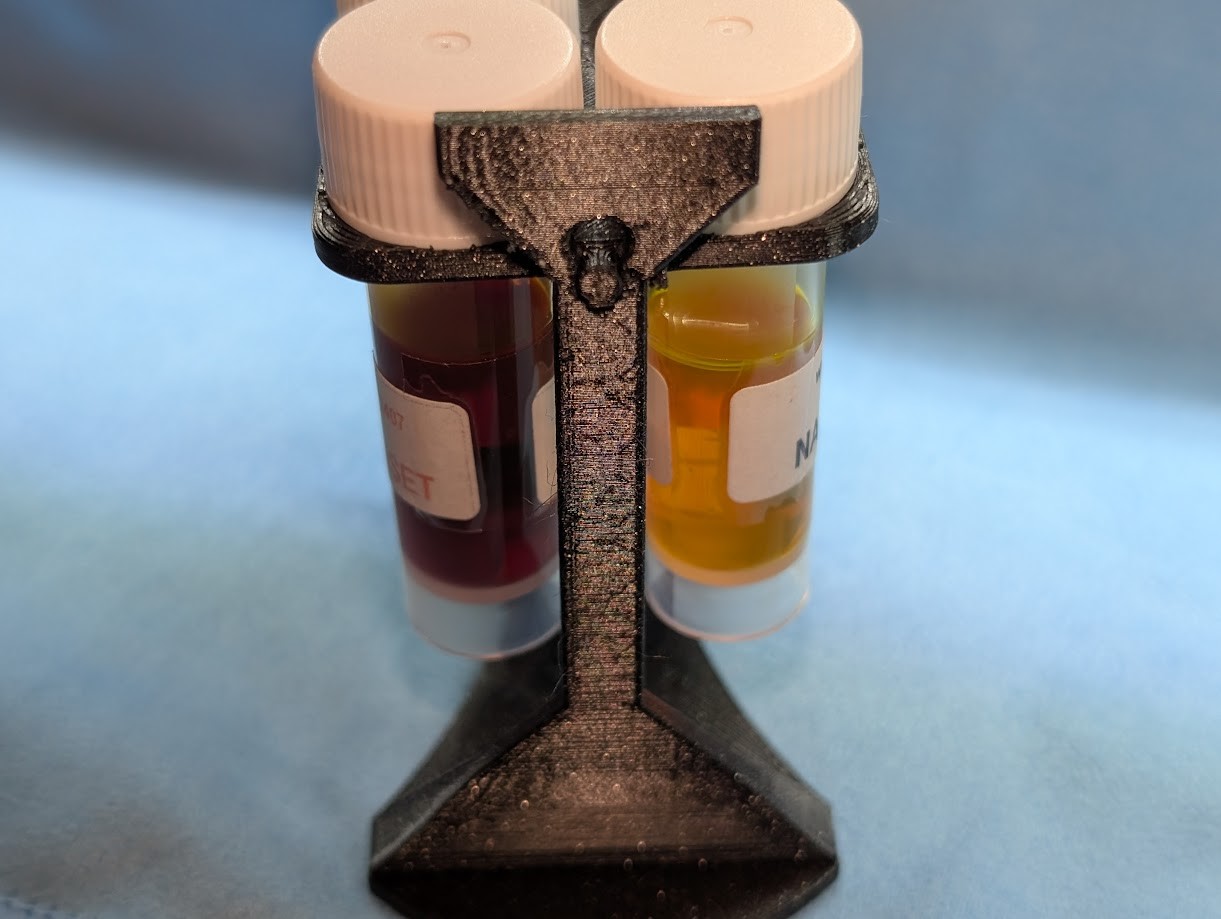 Photo of a 3D printed sample vial rack from the edge. There are sample vials in the rack. The side of the leg facing the camera has a rough texture and some signs of blobs/stringing.