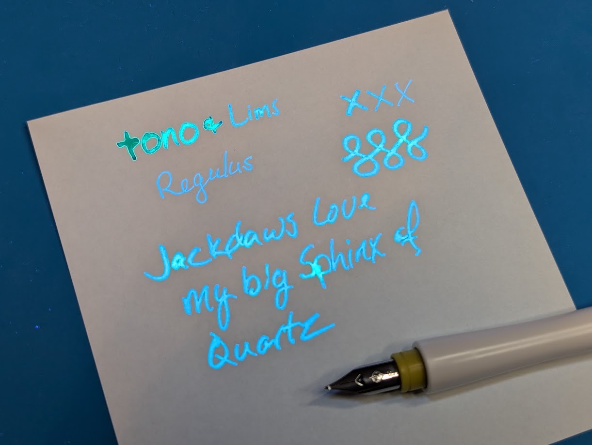 Same writing sample as before but under UV light since this ink is fluorescent. The thicker lines and areas are glowing greenish, the others are glowing blue.