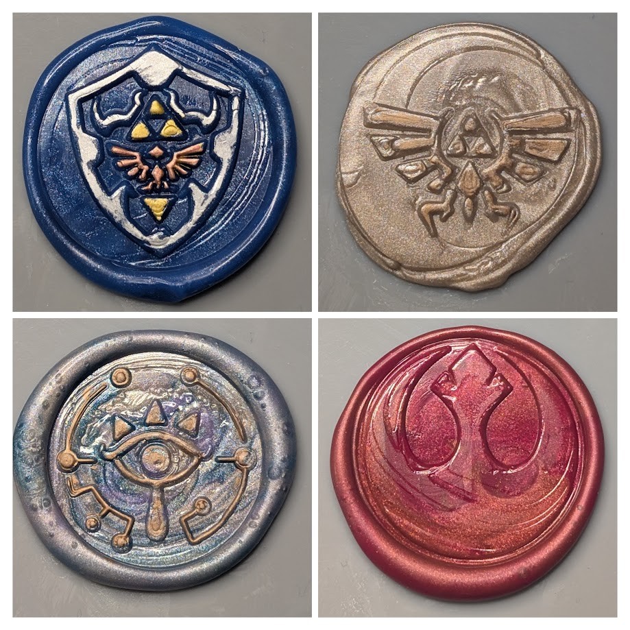 Photo collage of four wax seals made using stamps with various designs. Top left: A Hylean shield from Legend of Zelda video games. The base wax color is dark blue. The outline of the shield is colored silver, the triforce and triangles are gold, the Hylean crest is red. Top right: A larger Hylean crest from Legend of Zelda video games. Base wax color is bronze-ish, the crest itself is gold. Bottom left: A Sheikah Eye symbol from Legend of Zelda video games. The base wax color is a swirl of different blue shades with some sparkle. The details of the eye are colored in gold. Bottom right: The Rebel Alliance Starbird symbol from Star Wars. The base wax color is dark red with some bronze swirled in.