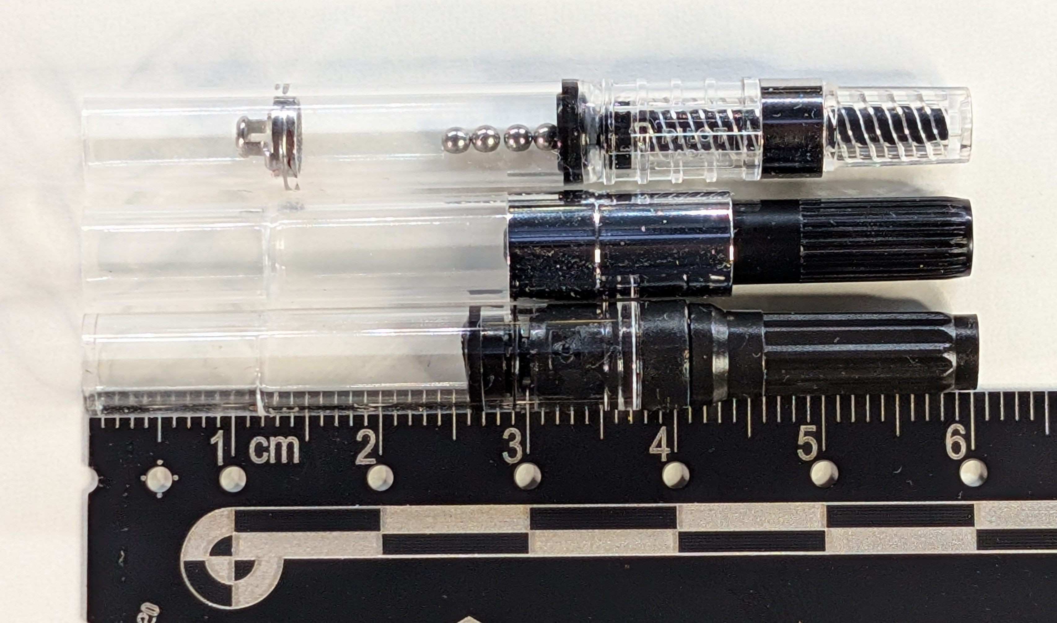 Photos of three fountain pen converters next to each other with their pistons retracted all next to a ruler. Top is a Pilot CON-40, the piston appears to be at about the 32mm mark on the ruler. Next is a Majohn A1, the piston appears to be at about the 28mm mark Last is a Jinhao 10, the piston appears to be at about the 25mm mark