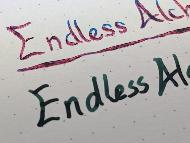 Writing sample on dot grid paper  First line is partially visible, reads "Endless Alch". The text is underlined with a variable-width line. The ink is blue and there is a noticeable reddish sheen on portions of the lines in the writing.  Second line is partially visible, reads "Endless Al". The ink is dark green.