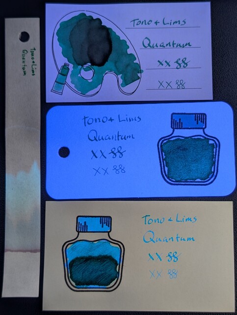 Same as the last photo but under a mix of visible and UV light.  The Iroful paper is glowing slightly and the ink swatch is glowing teal.  The col-o-ring paper is glowing brightly and the ink in the bottle is glowing greenish, the cap is glowing light blue, and the text is glowing more blue.  The Midori paper is not glowing, and the ink is glowing medium blue in the text, bottle cap, and top of bottle, while the bottom of the bottle is glowing more teal/green.  The chromatography strip has a dim greenish glow extending far past the end of where the blue was in the previous photo.
